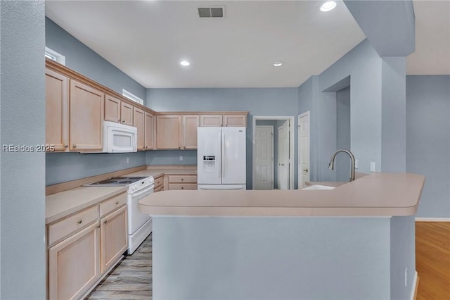 kitchen with a kitchen island with sink, light brown cabinetry, white appliances, and light hardwood / wood-style floors