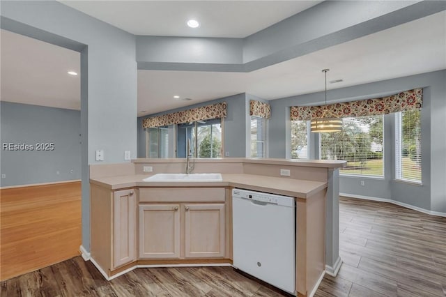 kitchen featuring sink, dishwasher, light brown cabinetry, kitchen peninsula, and light wood-type flooring