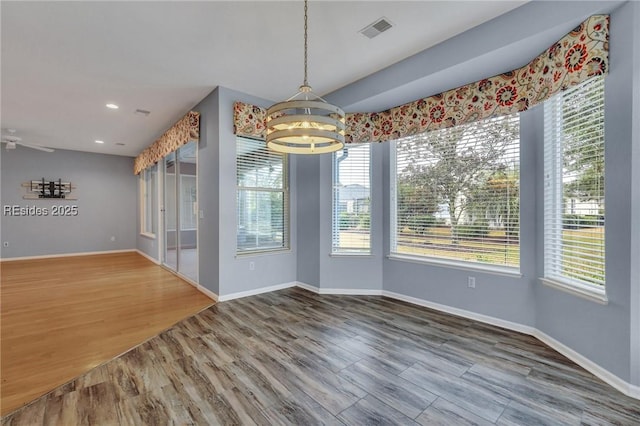 unfurnished dining area featuring hardwood / wood-style flooring and an inviting chandelier