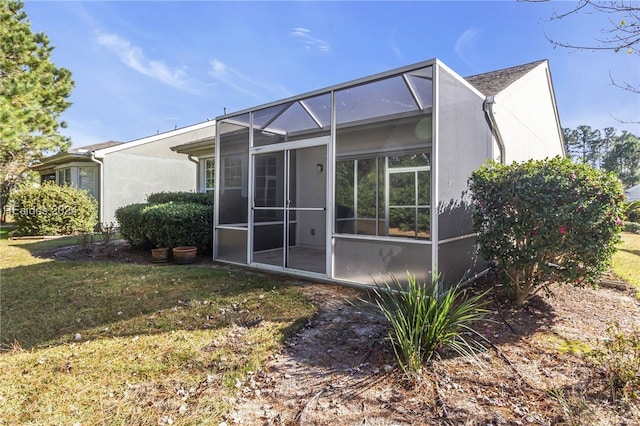 rear view of property featuring a lawn and glass enclosure