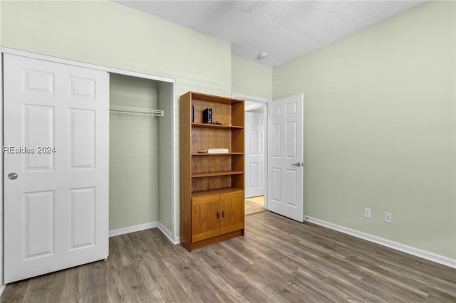 unfurnished bedroom with hardwood / wood-style flooring, a closet, and a textured ceiling