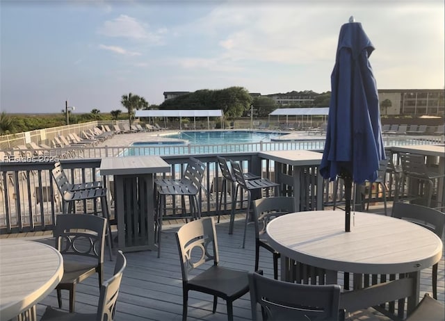 wooden deck featuring a community pool and a water view