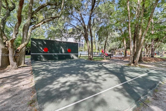 view of tennis court featuring a playground