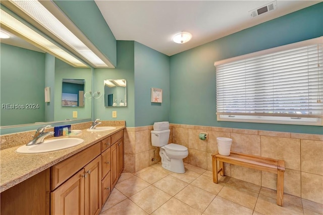 bathroom featuring tile patterned flooring, vanity, toilet, and tile walls