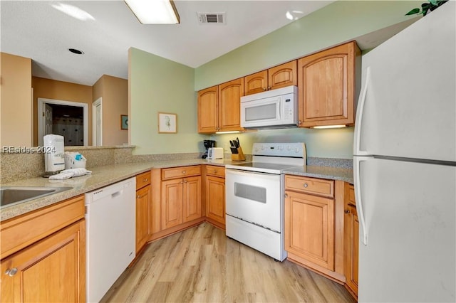 kitchen with light hardwood / wood-style flooring, white appliances, and kitchen peninsula