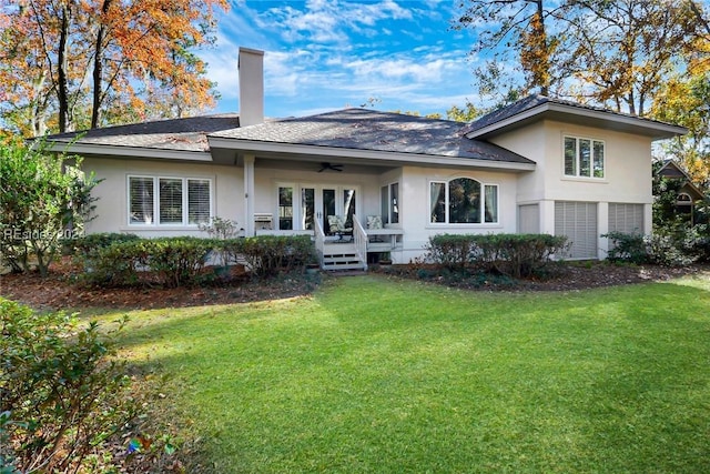 rear view of house featuring ceiling fan and a yard