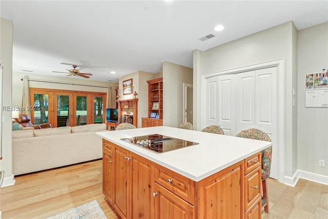 kitchen featuring french doors, a center island, light hardwood / wood-style flooring, black electric cooktop, and ceiling fan