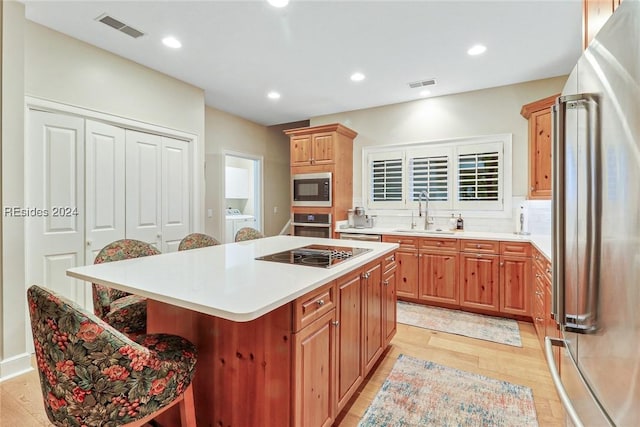 kitchen featuring a kitchen island, appliances with stainless steel finishes, sink, a breakfast bar area, and decorative backsplash