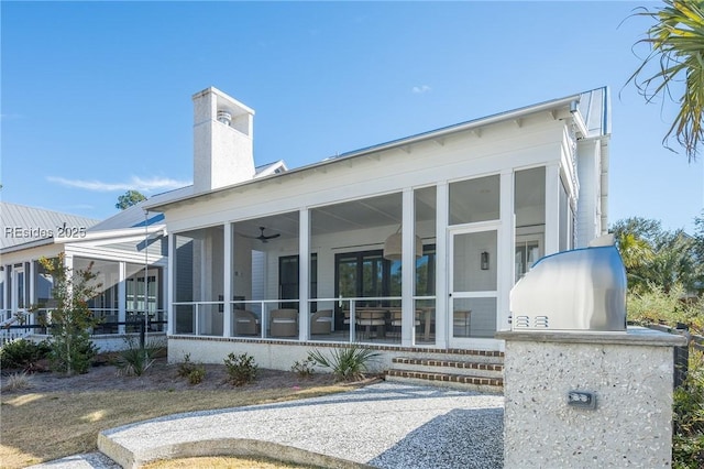 rear view of house with ceiling fan and a sunroom