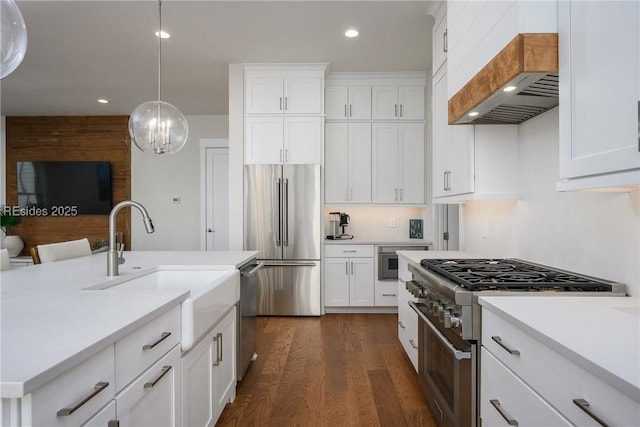 kitchen featuring stainless steel appliances, custom range hood, pendant lighting, and white cabinets