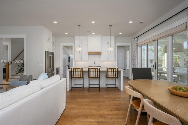 dining space with sink, a notable chandelier, and light hardwood / wood-style flooring