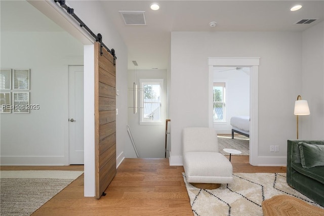 sitting room with a barn door and light wood-type flooring