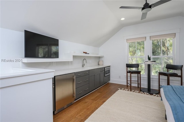 kitchen with stainless steel microwave, lofted ceiling, hardwood / wood-style flooring, fridge, and ceiling fan