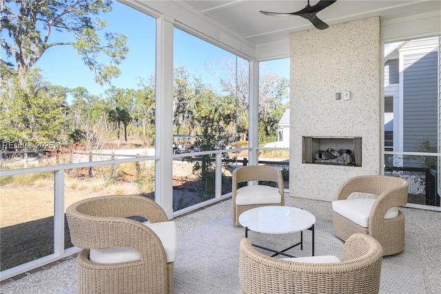 sunroom / solarium with a large fireplace, a wealth of natural light, and ceiling fan