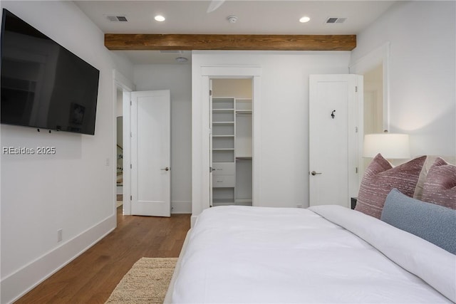 bedroom featuring beamed ceiling, a spacious closet, hardwood / wood-style floors, and a closet