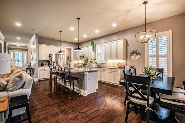 kitchen featuring a kitchen island, a breakfast bar area, backsplash, hanging light fixtures, and light stone counters