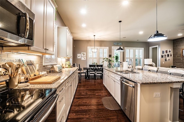 kitchen with sink, decorative light fixtures, a center island with sink, and appliances with stainless steel finishes