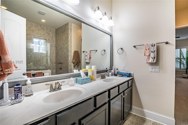 bathroom with tile patterned flooring, vanity, plenty of natural light, and a tile shower