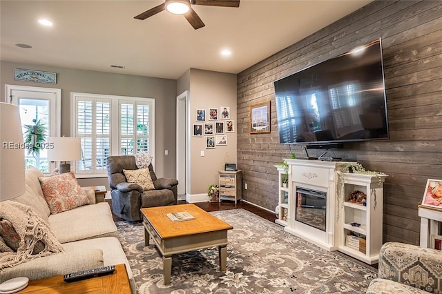 living room with ceiling fan and wood walls