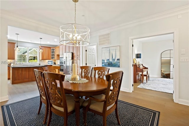 dining space with crown molding, a chandelier, and light hardwood / wood-style floors