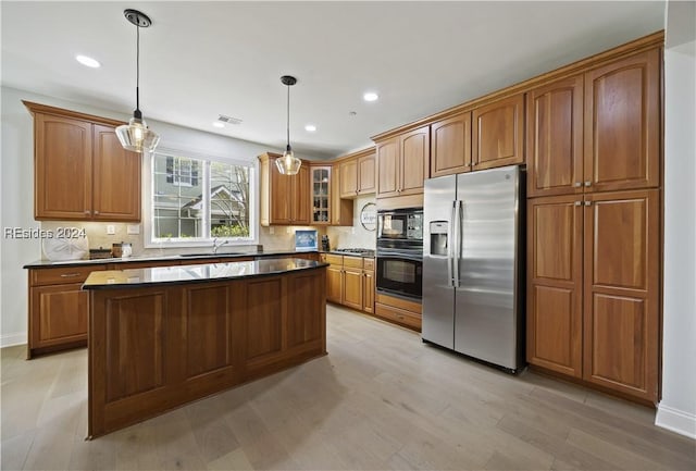 kitchen featuring sink, light hardwood / wood-style flooring, hanging light fixtures, black appliances, and decorative backsplash