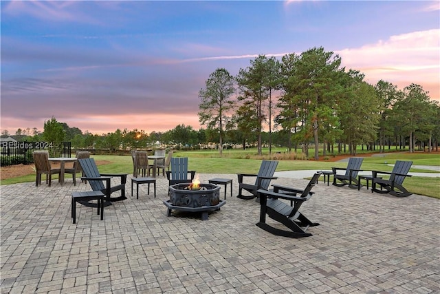 patio terrace at dusk with a fire pit and a lawn