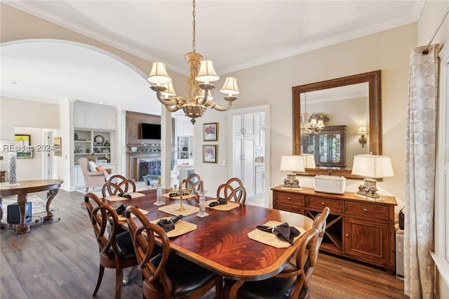 dining area with dark hardwood / wood-style flooring, a notable chandelier, crown molding, and a fireplace