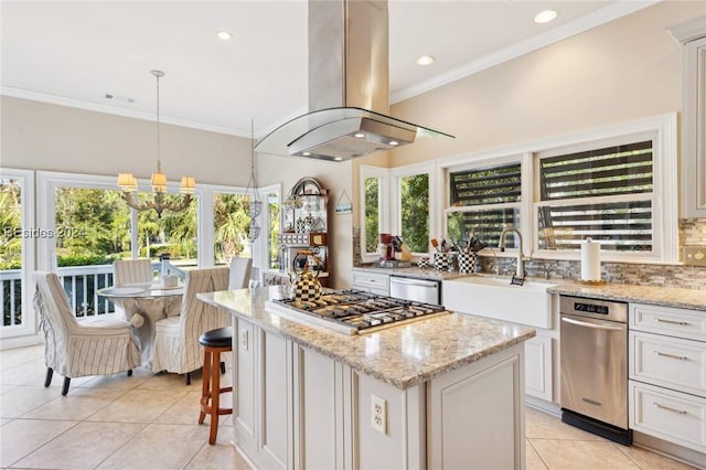 kitchen with appliances with stainless steel finishes, white cabinetry, island range hood, light stone countertops, and a kitchen island