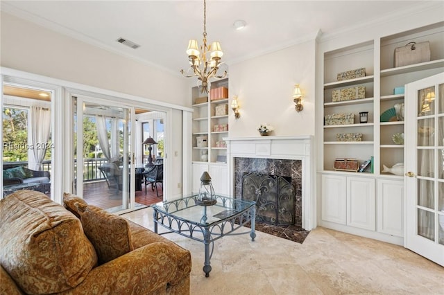 living room featuring built in shelves, ornamental molding, a premium fireplace, and an inviting chandelier