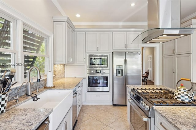 kitchen featuring sink, light stone counters, island range hood, stainless steel appliances, and white cabinets