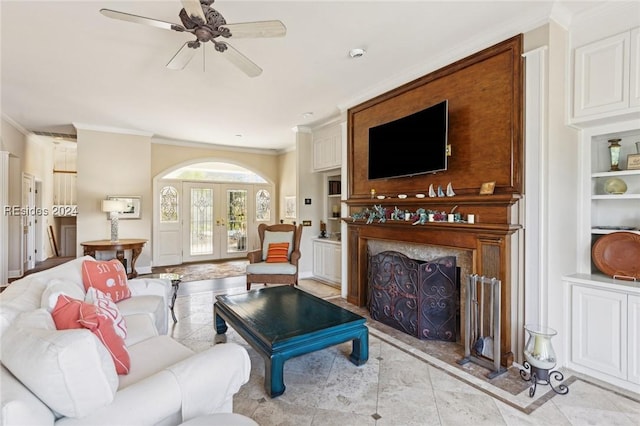 living room with built in shelves, ornamental molding, french doors, and ceiling fan