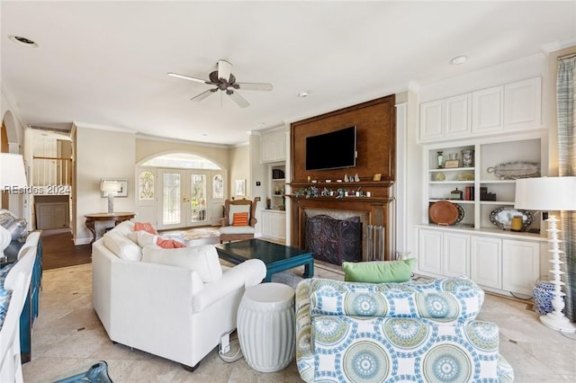 living room featuring crown molding, built in features, french doors, and ceiling fan