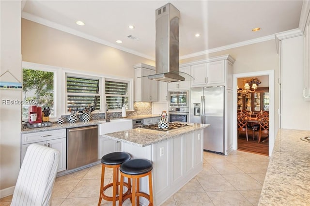 kitchen with a kitchen island, island exhaust hood, stainless steel appliances, light stone countertops, and white cabinets