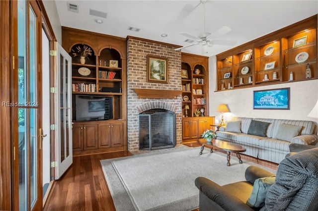 living room with dark hardwood / wood-style flooring, ceiling fan, a fireplace, and built in shelves