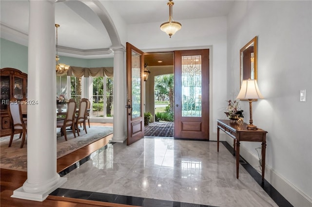 foyer with ornate columns, ornamental molding, and an inviting chandelier