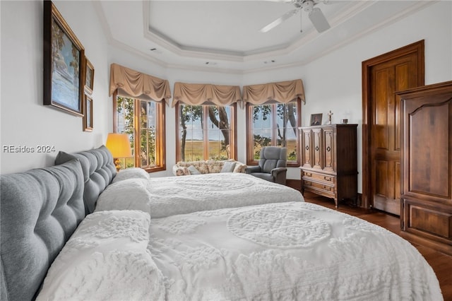 bedroom featuring dark wood-type flooring, ceiling fan, ornamental molding, and a tray ceiling