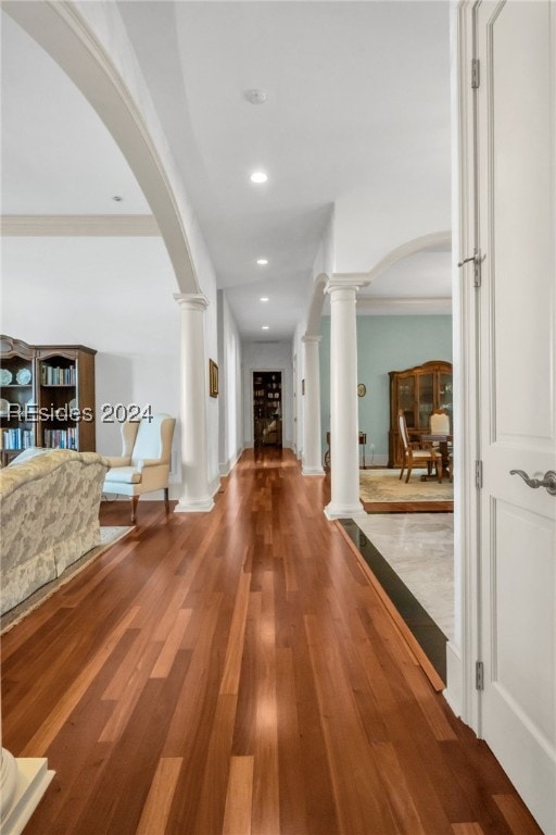 corridor with hardwood / wood-style flooring, crown molding, and ornate columns