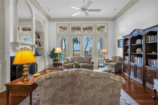 sitting room with crown molding, built in shelves, dark wood-type flooring, and ceiling fan