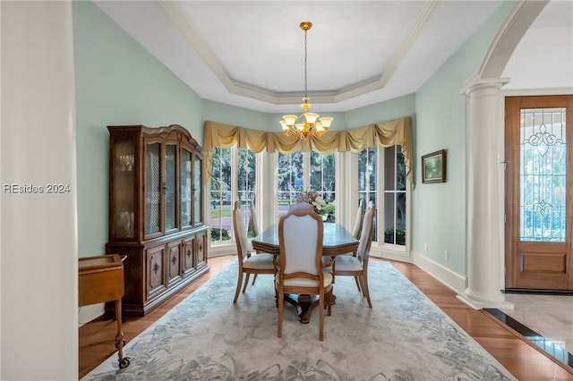 dining room with a healthy amount of sunlight, a tray ceiling, and ornate columns