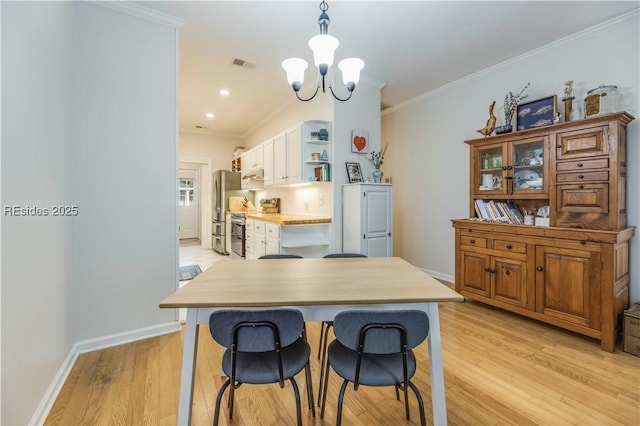 kitchen featuring stainless steel appliances, ornamental molding, a chandelier, and light hardwood / wood-style flooring