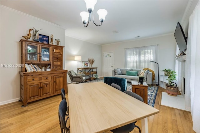 dining space with crown molding, an inviting chandelier, and light wood-type flooring