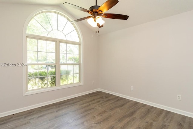 empty room with ceiling fan, dark hardwood / wood-style flooring, and vaulted ceiling