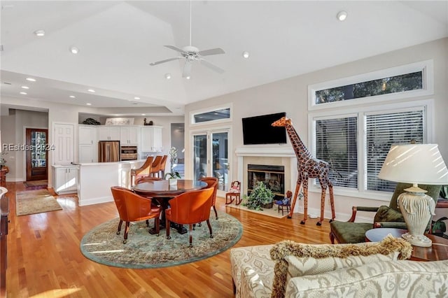 living room featuring ceiling fan, vaulted ceiling, and light hardwood / wood-style flooring