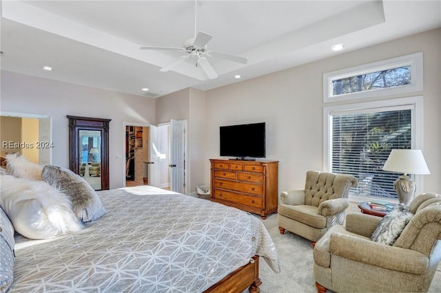 carpeted bedroom featuring a closet, a spacious closet, a raised ceiling, and ceiling fan