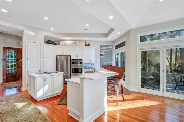 kitchen featuring white cabinetry, sink, a kitchen island with sink, light hardwood / wood-style floors, and stainless steel appliances