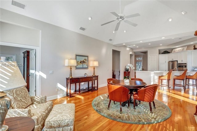 dining room with ceiling fan, lofted ceiling, and light wood-type flooring