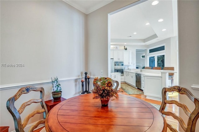 dining room featuring ornamental molding, sink, and light hardwood / wood-style flooring