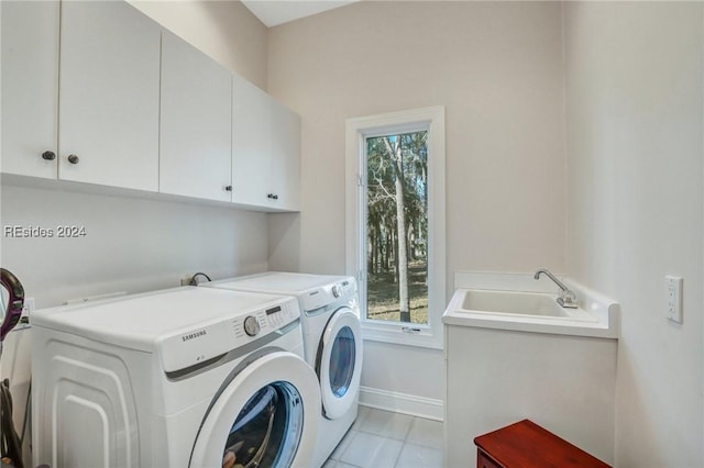 clothes washing area with independent washer and dryer, light tile patterned floors, a wealth of natural light, and cabinets