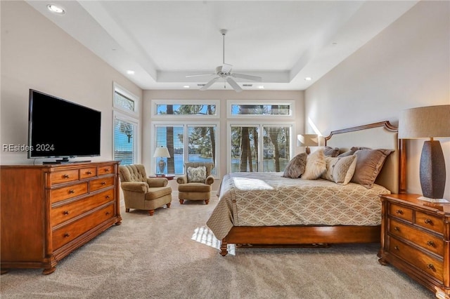 carpeted bedroom with a towering ceiling, ceiling fan, and a tray ceiling