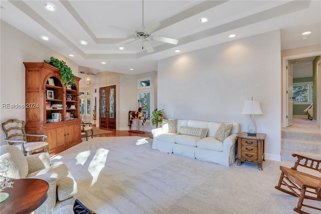 living room with a tray ceiling and ceiling fan